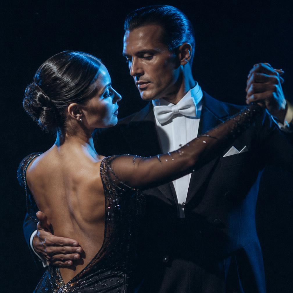 Ballroom couple in a close hold under blue rim light